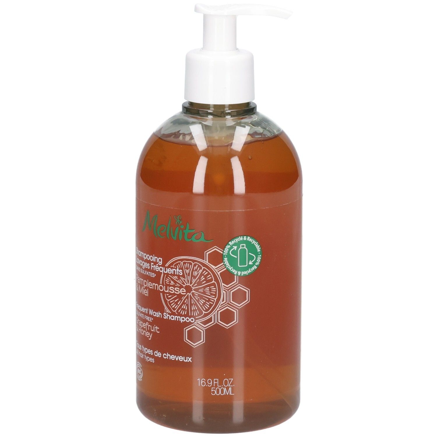 Duidelijke fles met witte pompdop, gevuld met amberkleurige vloeistof. Etiket met "Melvita"-logo, grapefruit- en honingraatmotief.