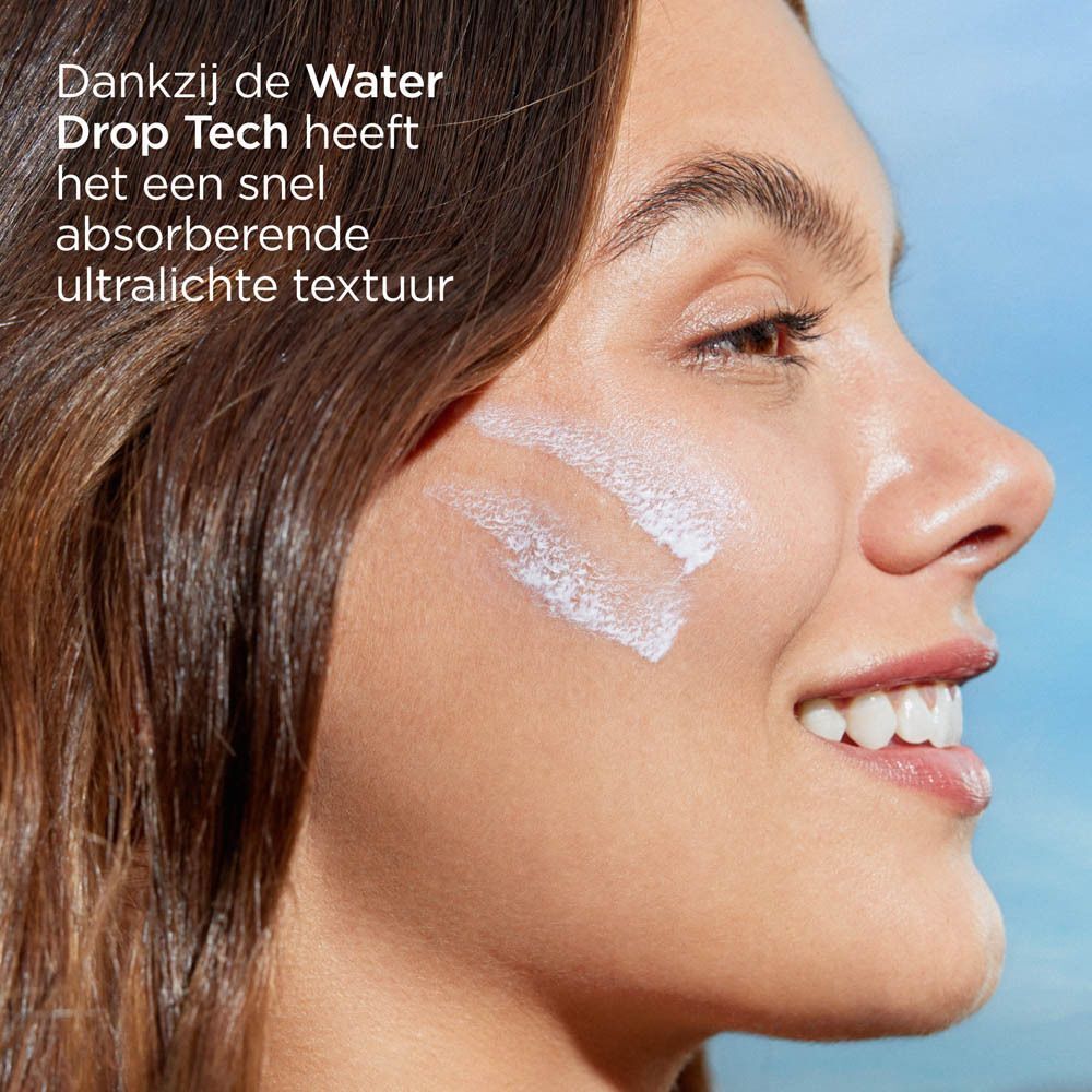 Een vrouw brengt ISDIN Fusion Water zonnebrandcrème aan op haar wang.
