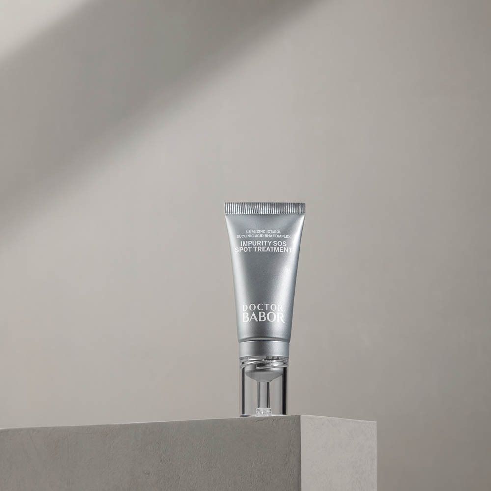 Zilveren tube met transparante applicator op een sokkel. Opschrift: Impurity SOS Spot Treatment, Doctor Babor.