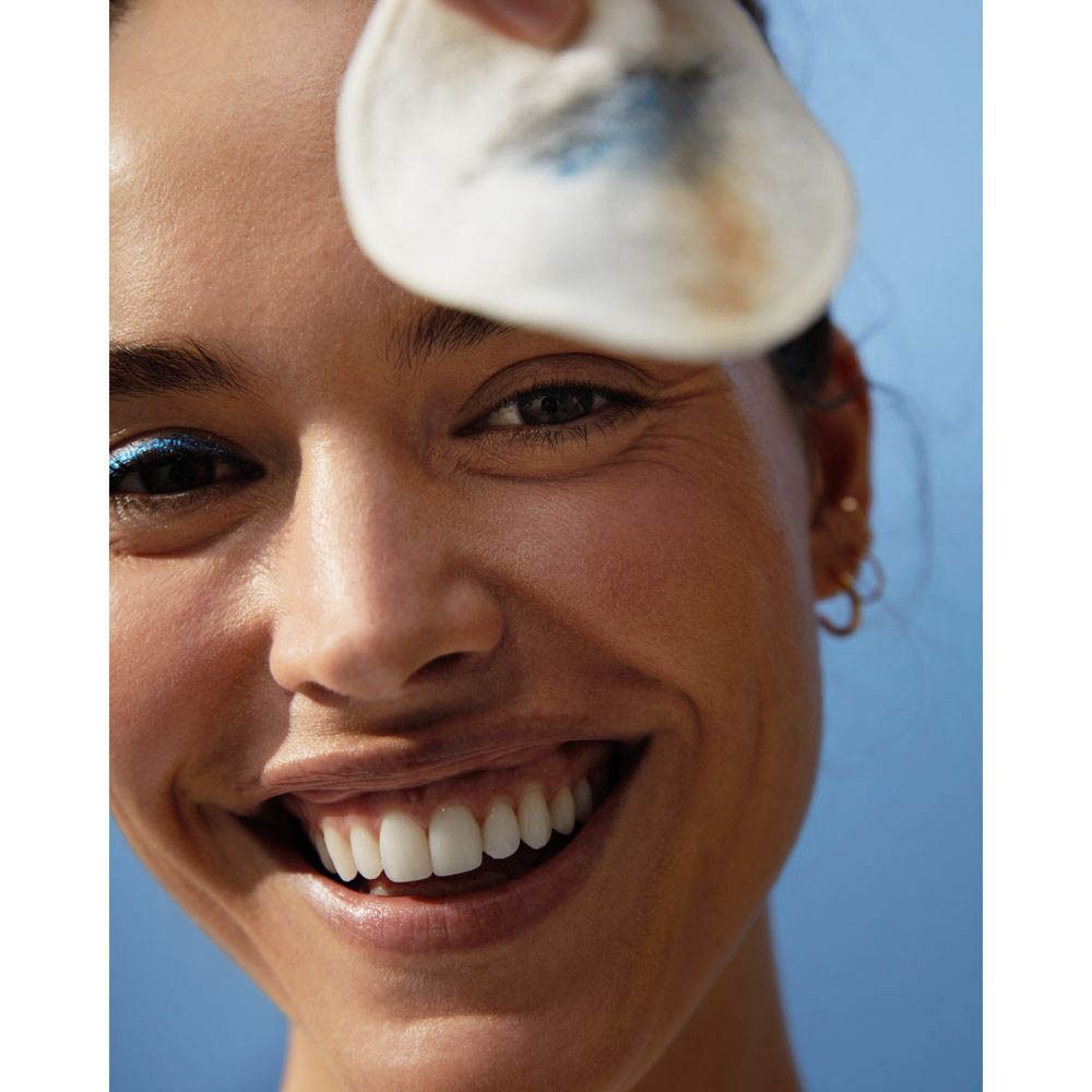 Vrouw houdt een wattenschijfje met make-upresten voor haar oog. Nivea Skin Glow Micellair Water.
