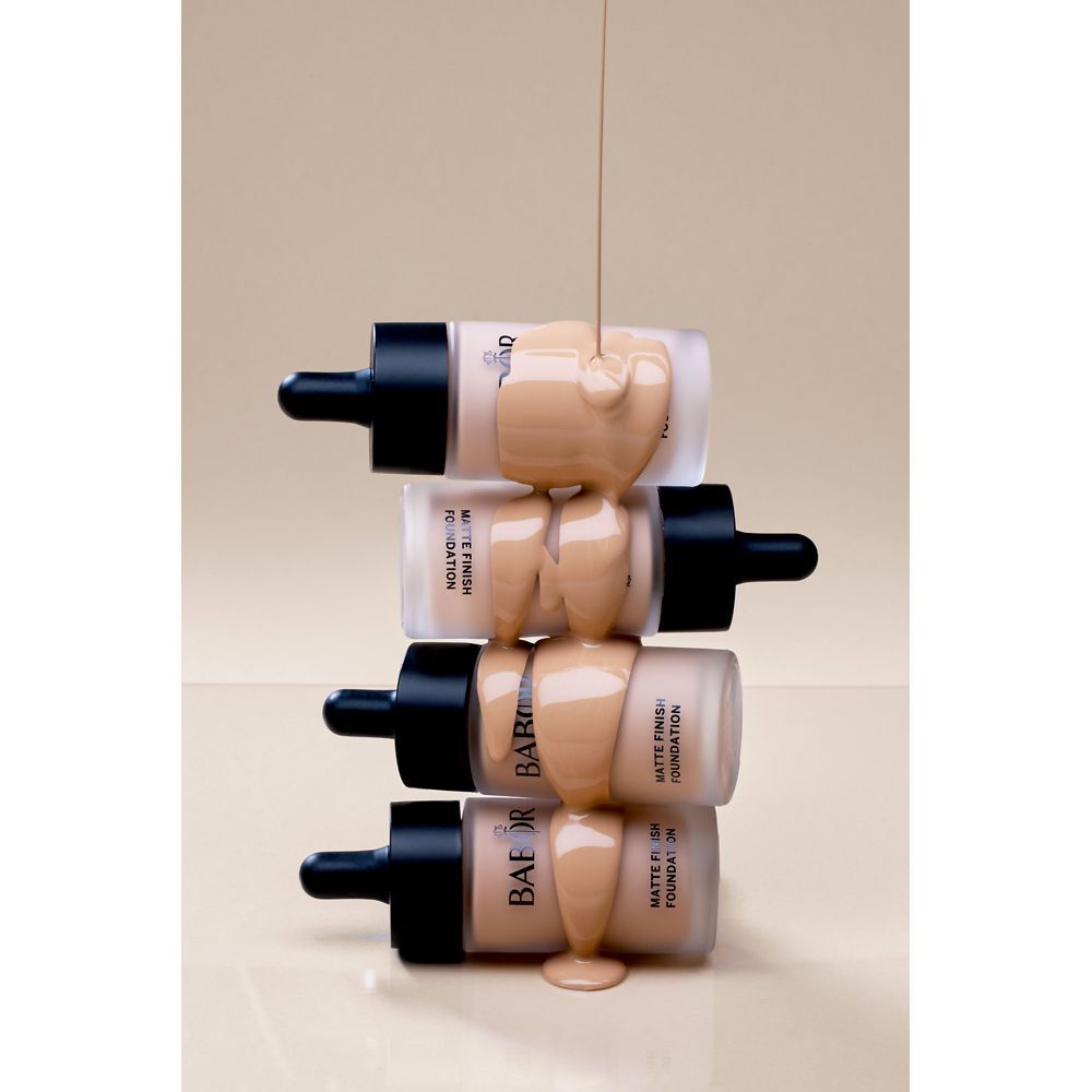 Foundationflesjes worden overgoten met foundation. Meerdere flessen. Beige foundation.