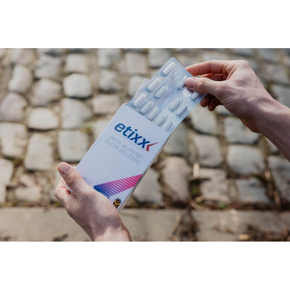 Handen openen een pak Etixx Beta Alanine Slow Release, onthullen blisterverpakkingen met tabletten.