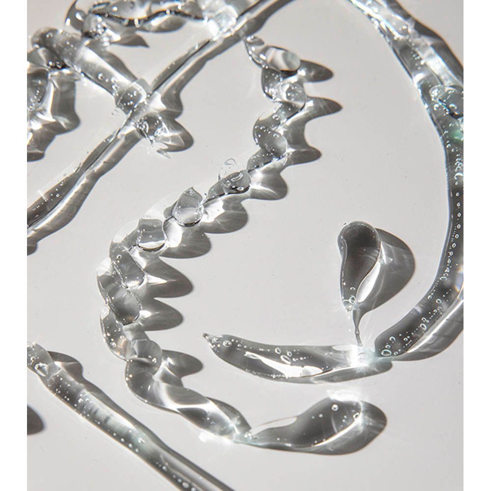 Gouttes de gel transparent sur fond blanc. Plusieurs gouttes forment une forme incurvée. Surface brillante.