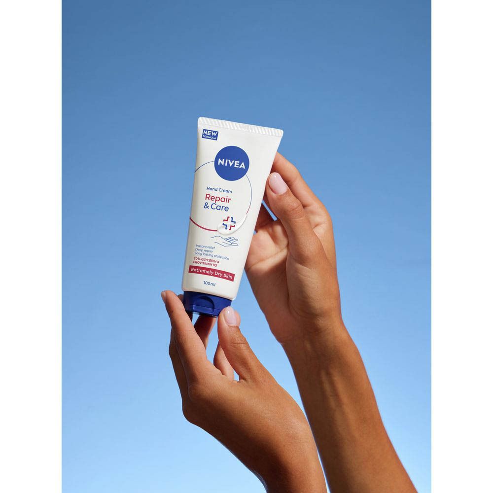 Mains tenant un tube Nivea Crème mains Réparation & Soin devant un ciel bleu.