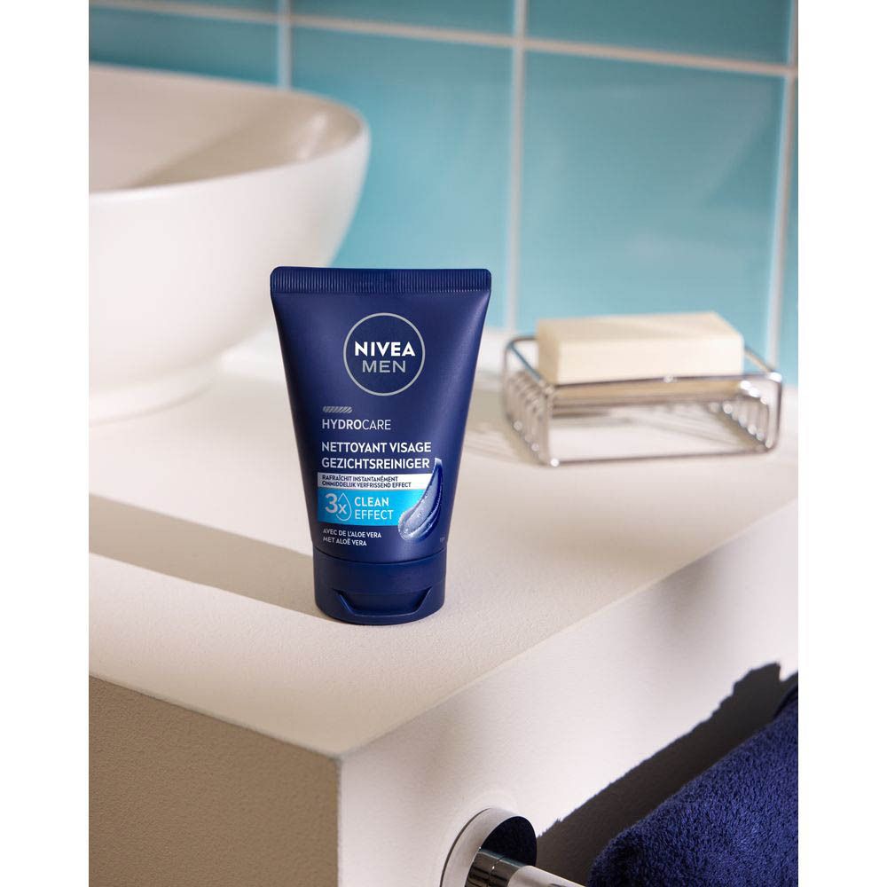 Blauwe tube met NIVEA MEN logo op een wit oppervlak. Op de achtergrond een wastafel en zeep.
