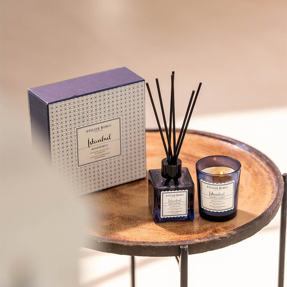 Productset: doos, kaars en diffuser. Geplaatst op een tafel.