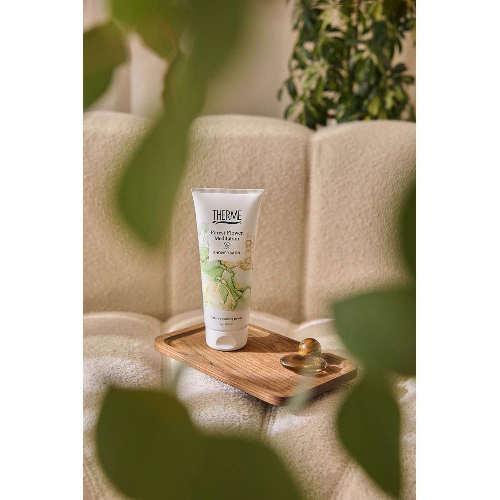 Produit sur un plateau en bois. En arrière-plan, un canapé et des plantes. Le produit est un tube.
