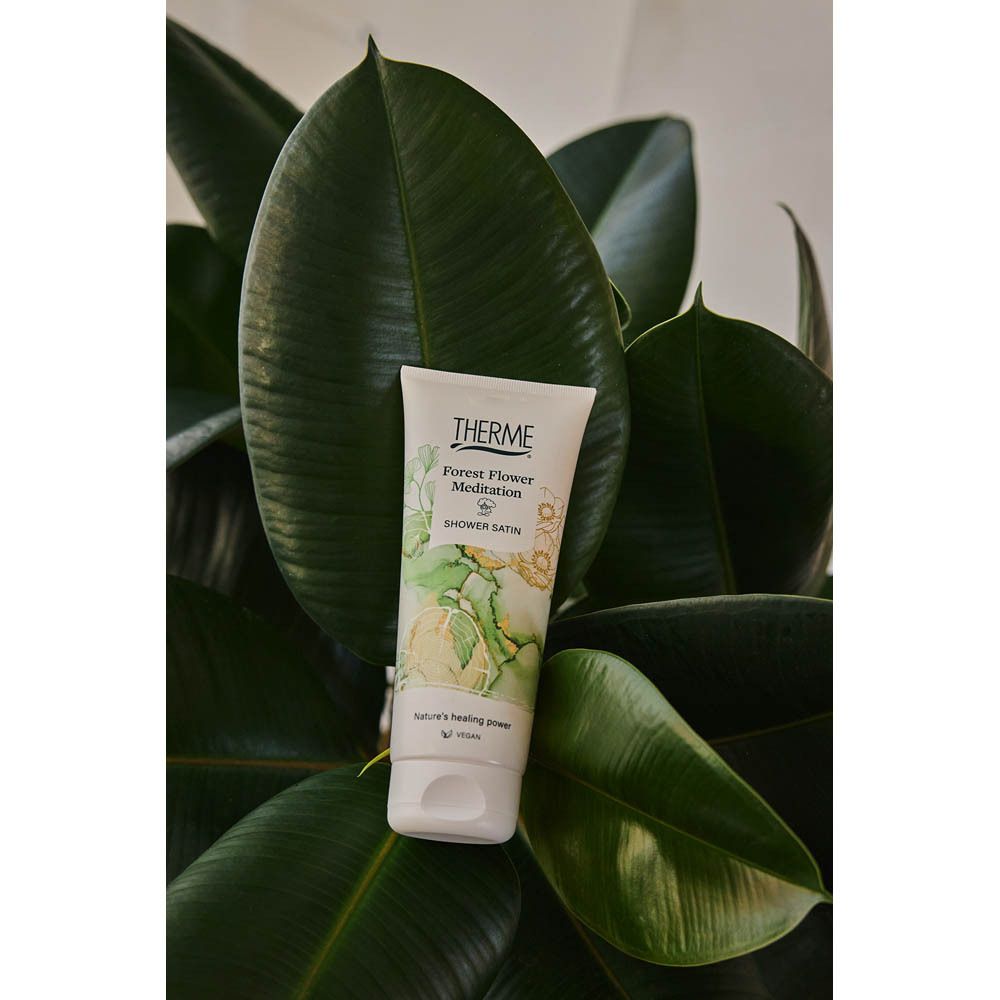 Un tube devant des feuilles vertes. Le produit est un tube avec le logo THERME et le nom du produit.