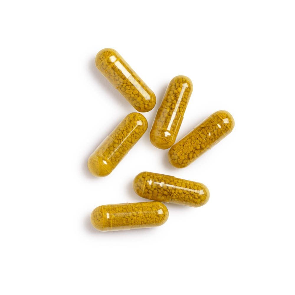 Zes gele CurcumRx-capsules op een witte achtergrond.