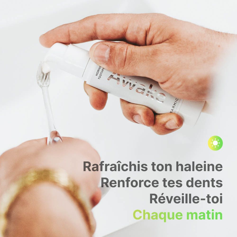 Personne se brossant les dents avec du dentifrice blanc. Inscription : Awake. Marque : Karmicare. Texte en français.