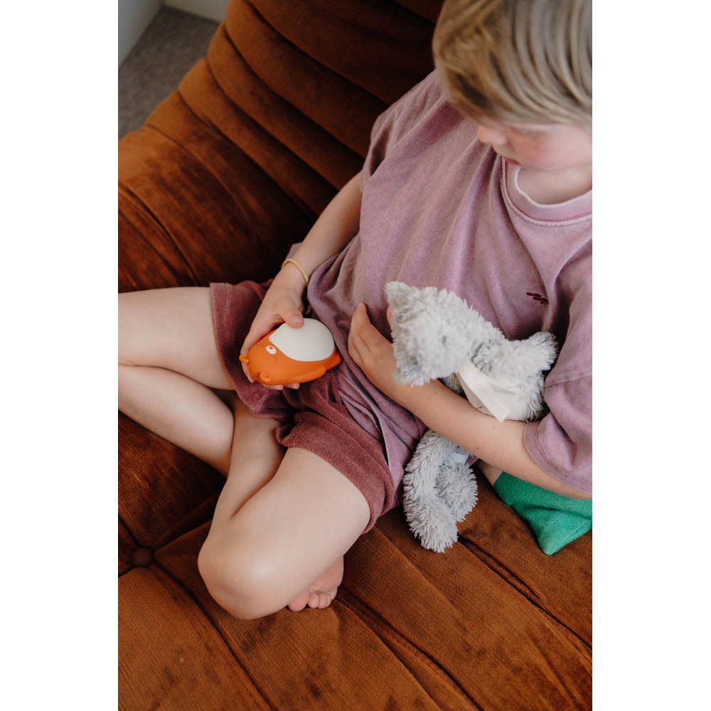 Moonbird Moonbuddy Barry l'ours, oranje en wit. Zittend op een bank.