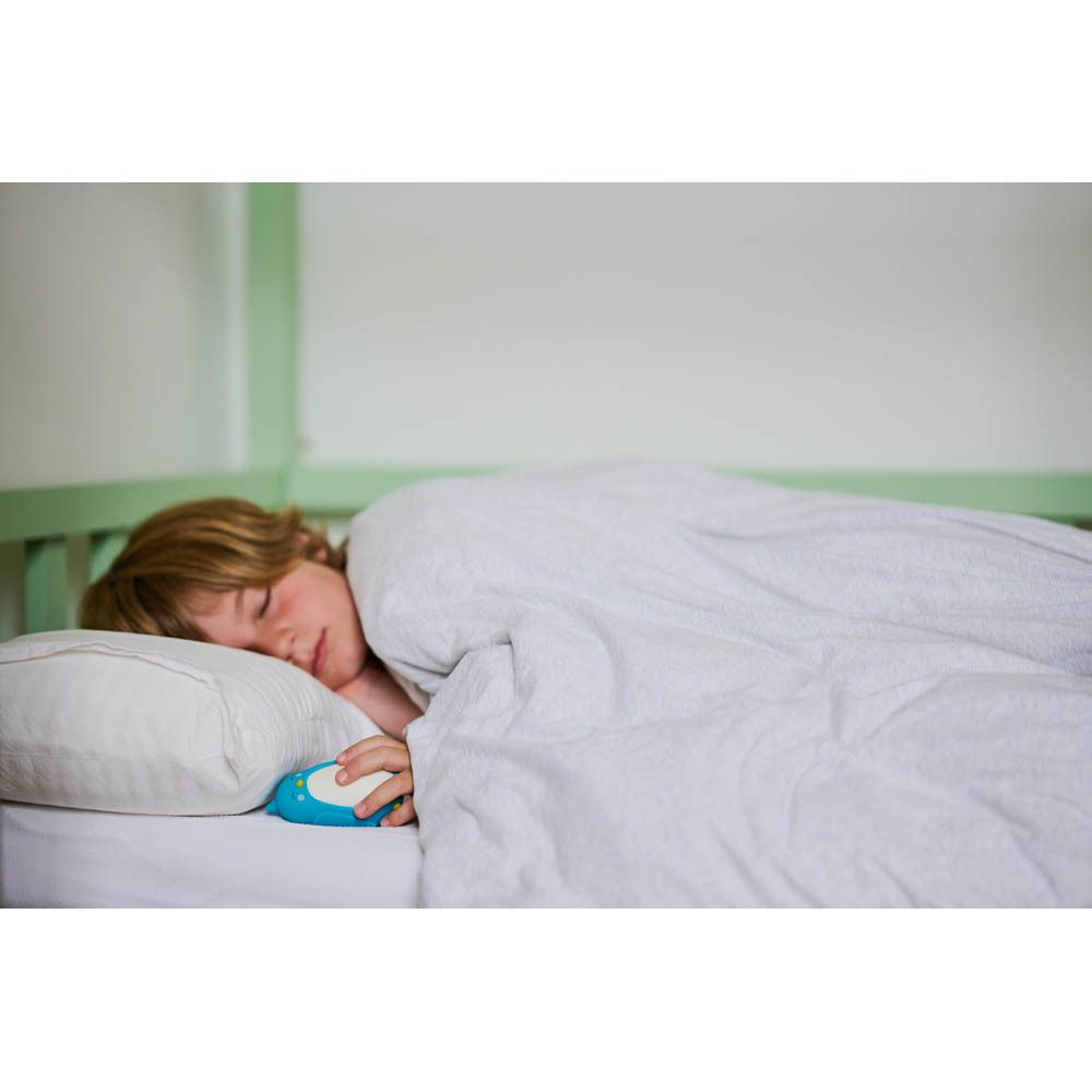 Jongen ligt in bed, houdt blauw Bibi-apparaat vast.