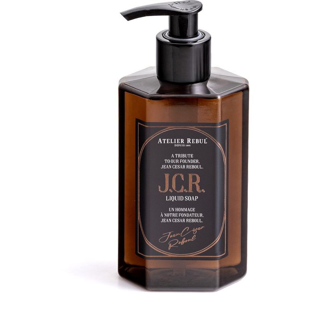 Bruine, zeshoekige vloeibare zeepfles met zwarte pomp. Etiket met tekst: Atelier Rebul J.C.R. Liquid Soap.