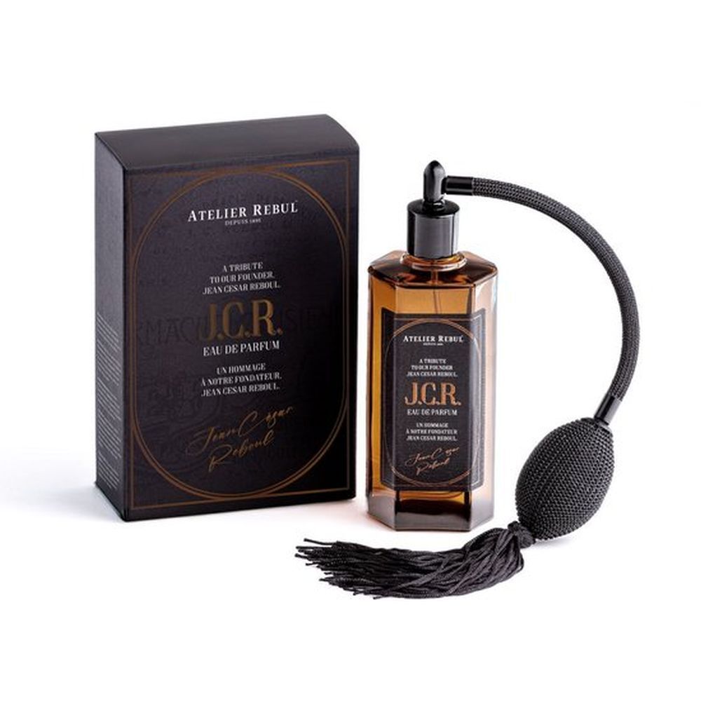 Parfumfles en doos. Fles met verstuiver. Zwarte doos met gouden kader. Tekst: Atelier Rebul, J.C.R. Eau de Parfum.