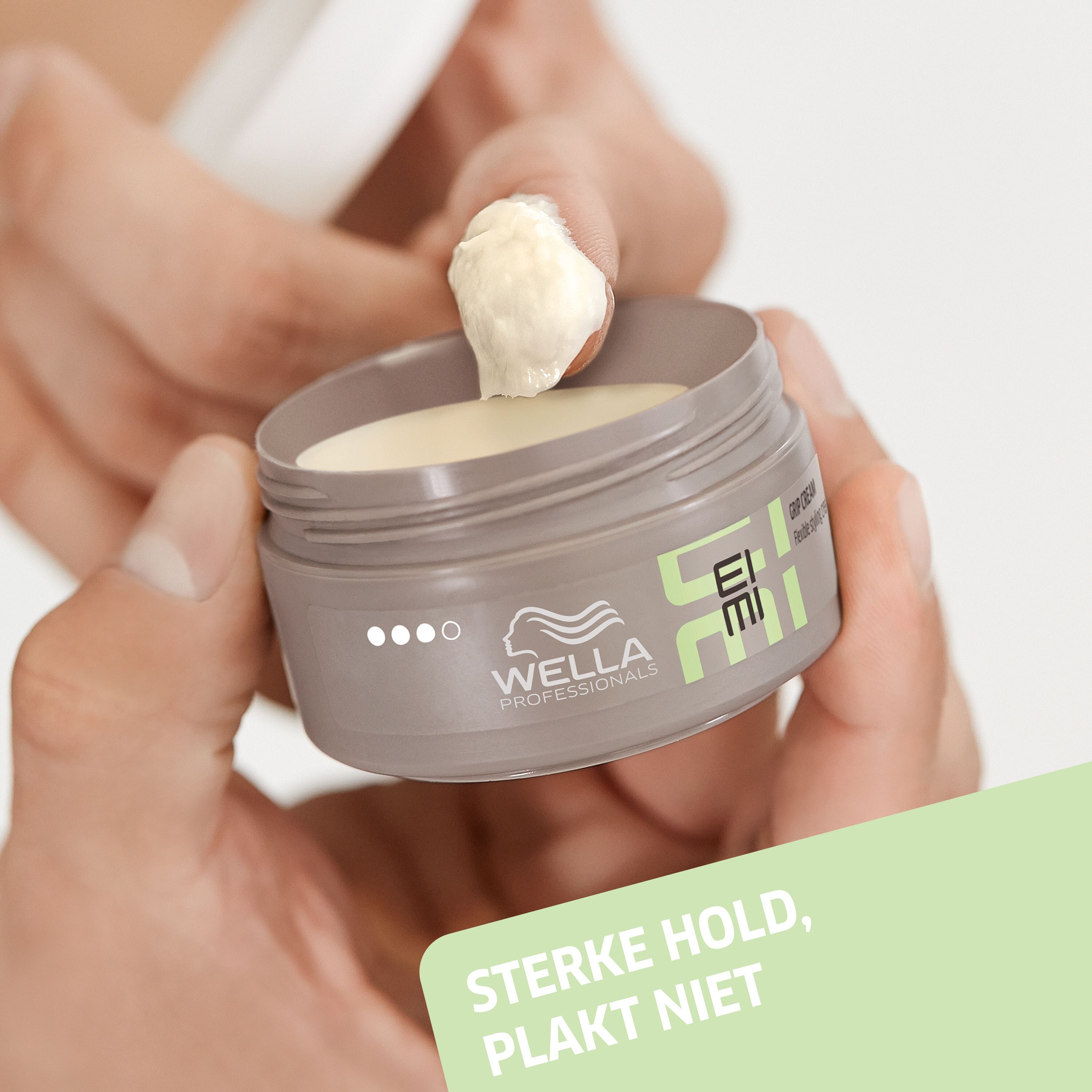 Handen houden een open pot. Product wordt uitgenomen. Opschrift: EIMI, Grip Cream. Tekst: Sterke hold, plakt niet.