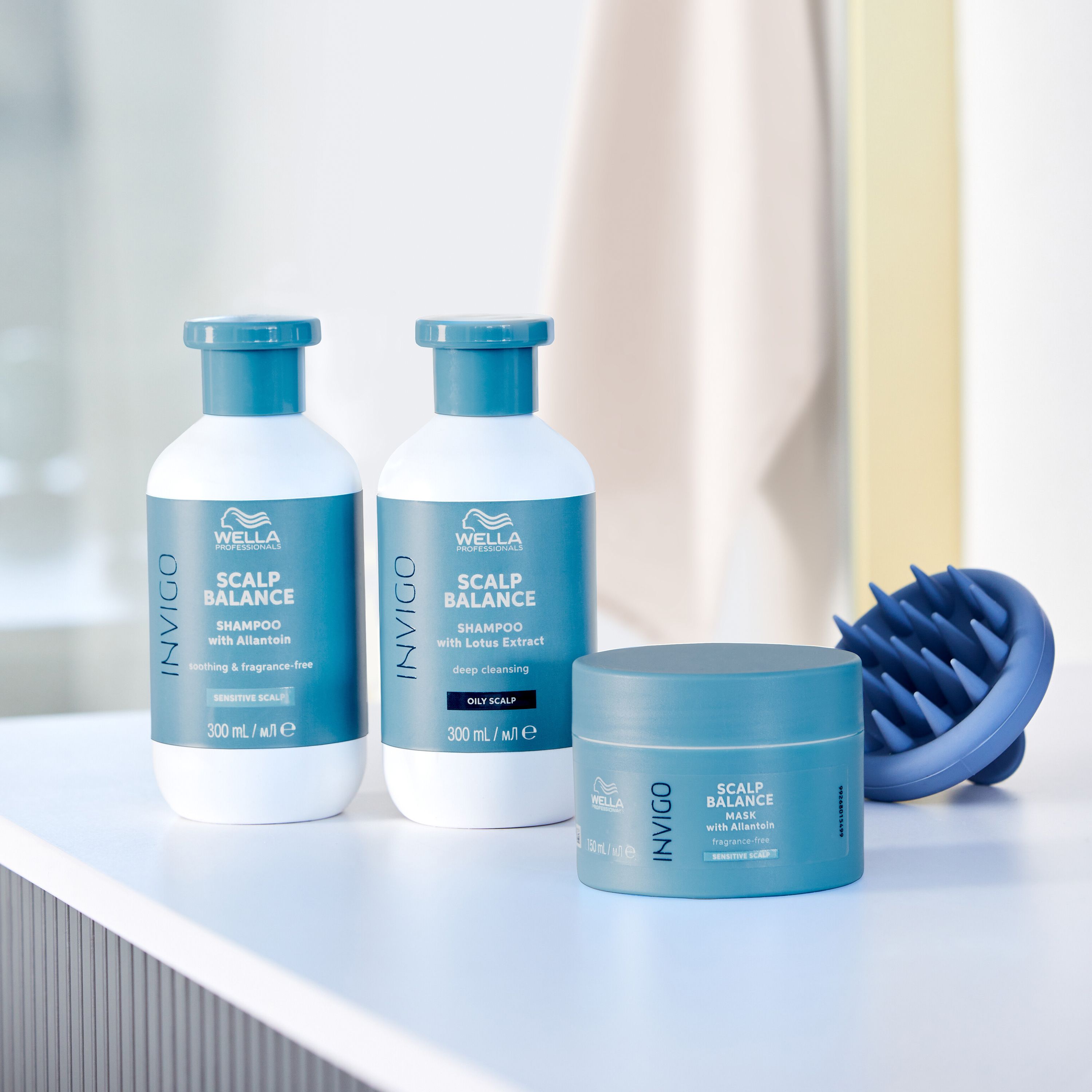 Ensemble de produits : deux flacons de shampooing, un pot de masque et une brosse pour le cuir chevelu bleue. Inscription : Invigo Scalp Balance.