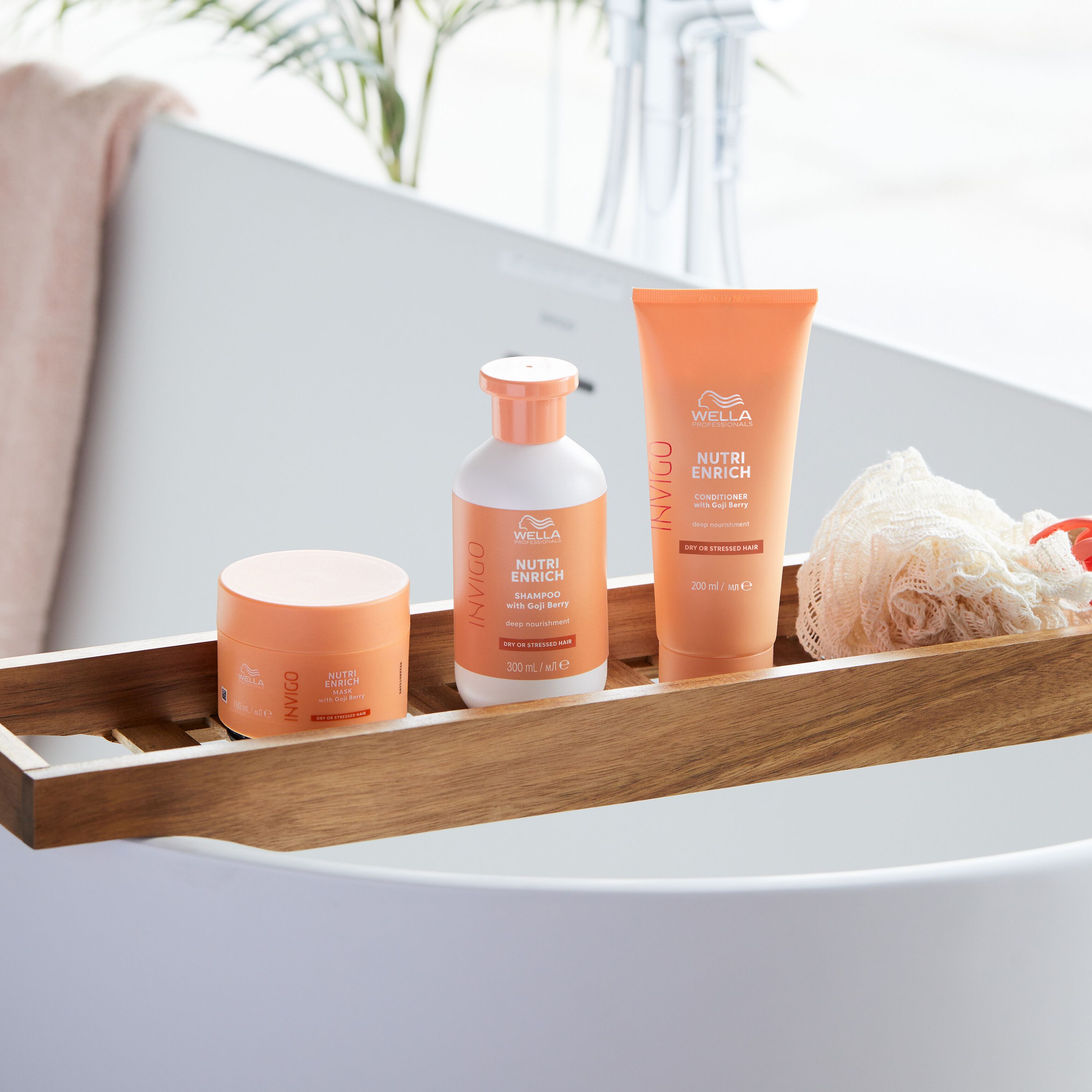 Trois produits Wella Invigo sur un plateau. Shampooing, après-shampooing et masque. Fond de salle de bain.