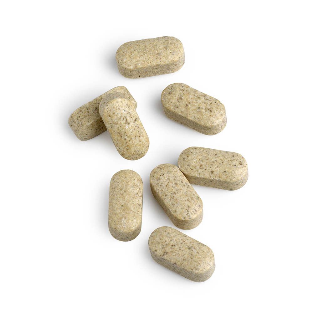 Meerdere ovale, beige tabletten met zichtbare deeltjes, op een witte achtergrond.