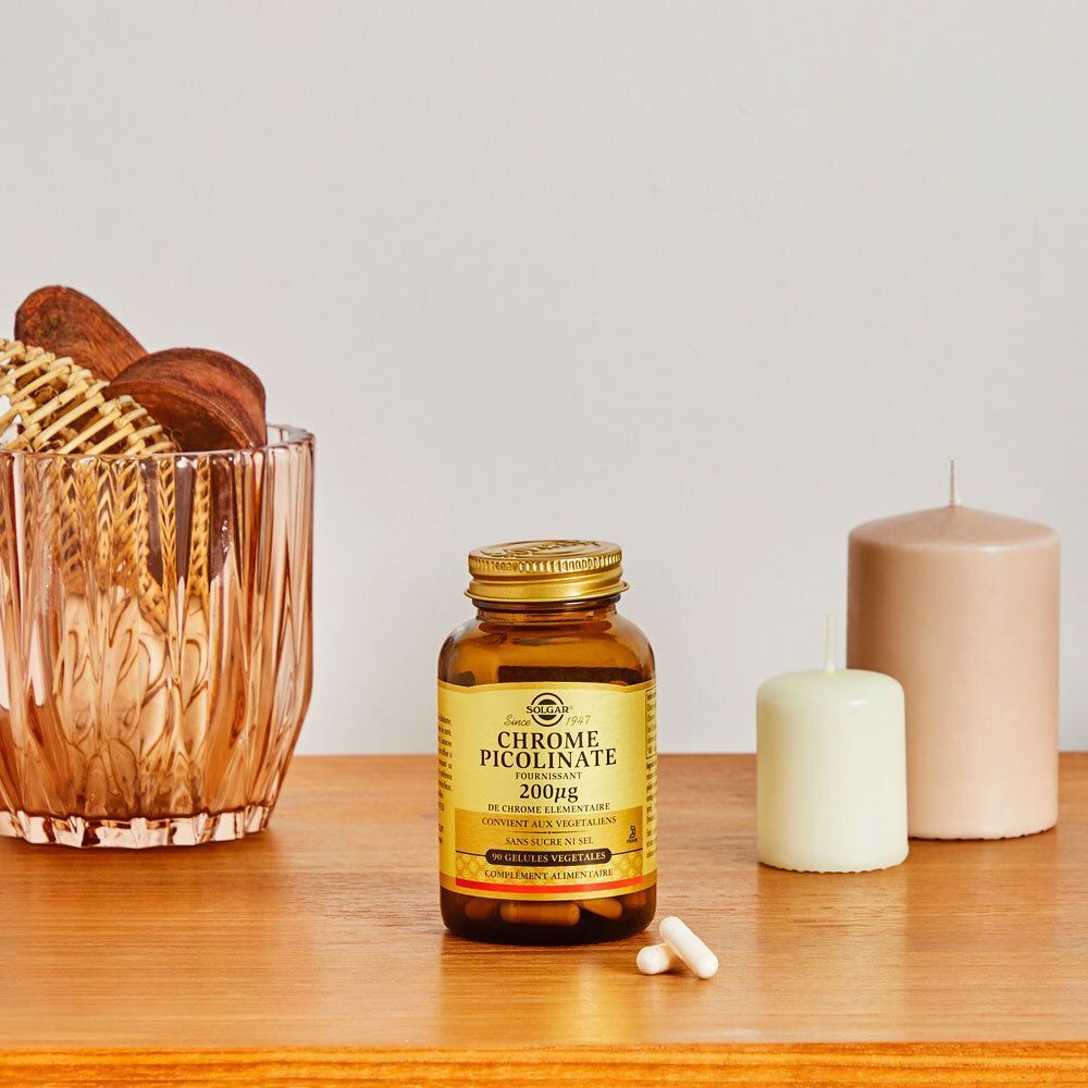 Een fles Solgar Chrome Picolinate op een tafel met kaarsen en decoratie. Bruine glazen fles met gouden dop.