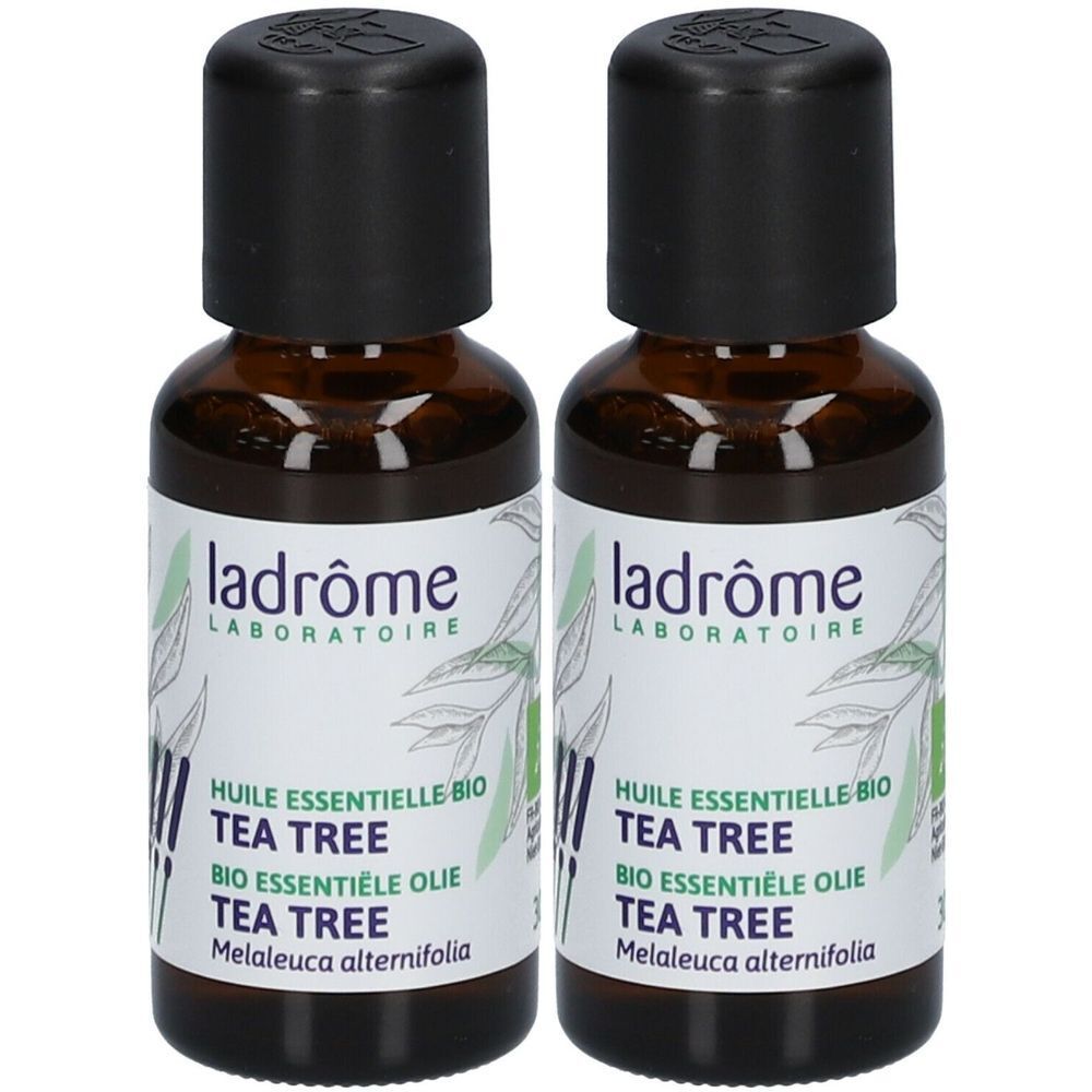 Twee bruine glazen flessen met zwarte doppen. De etiketten tonen "ladrôme LABORATOIRE" en "TEA TREE".