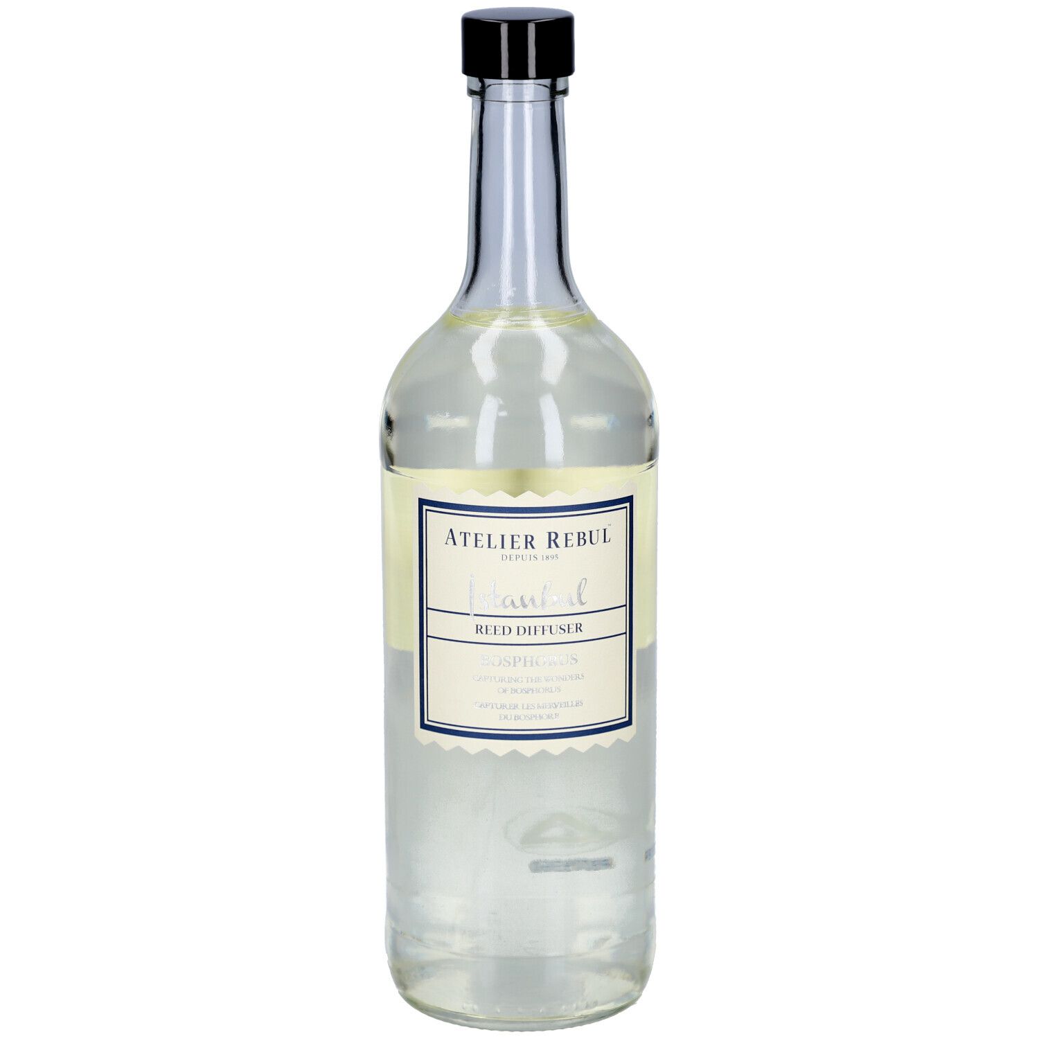 Glazen fles met zwarte dop en etiket. Opschrift: Atelier Rebul, Istanbul, Reed Diffuser.