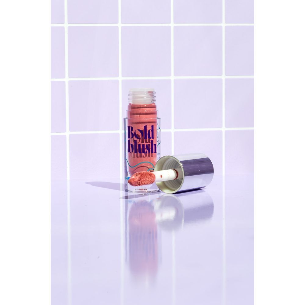 Vloeibare blush met applicator. Fles met zilveren dop. Opschrift: Bold blush, JONES. Achtergrond: tegels.