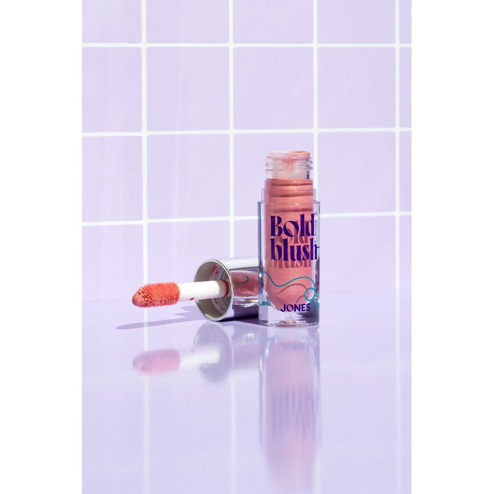 Fard à joues liquide avec applicateur. Inscription : Bold blush, JONES. Fond carrelé.