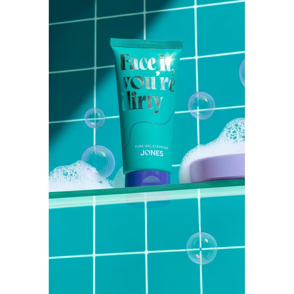 Turquoise tube met "Face it, you're dirty" in een badkameromgeving. Zeepbellen en zeep.