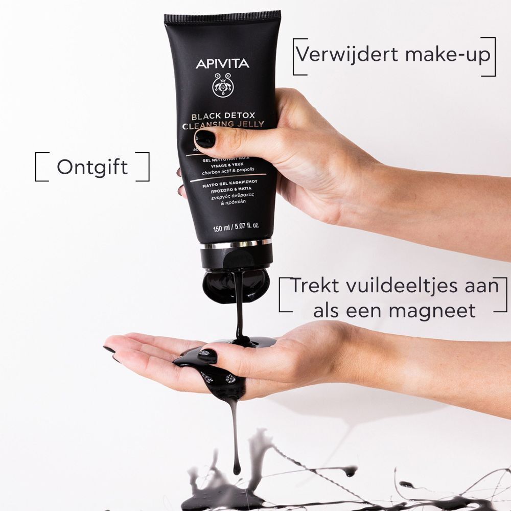 Handen houden een tube APIVITA Black Detox reinigingsgel vast. Zwarte gel wordt eruit geperst.