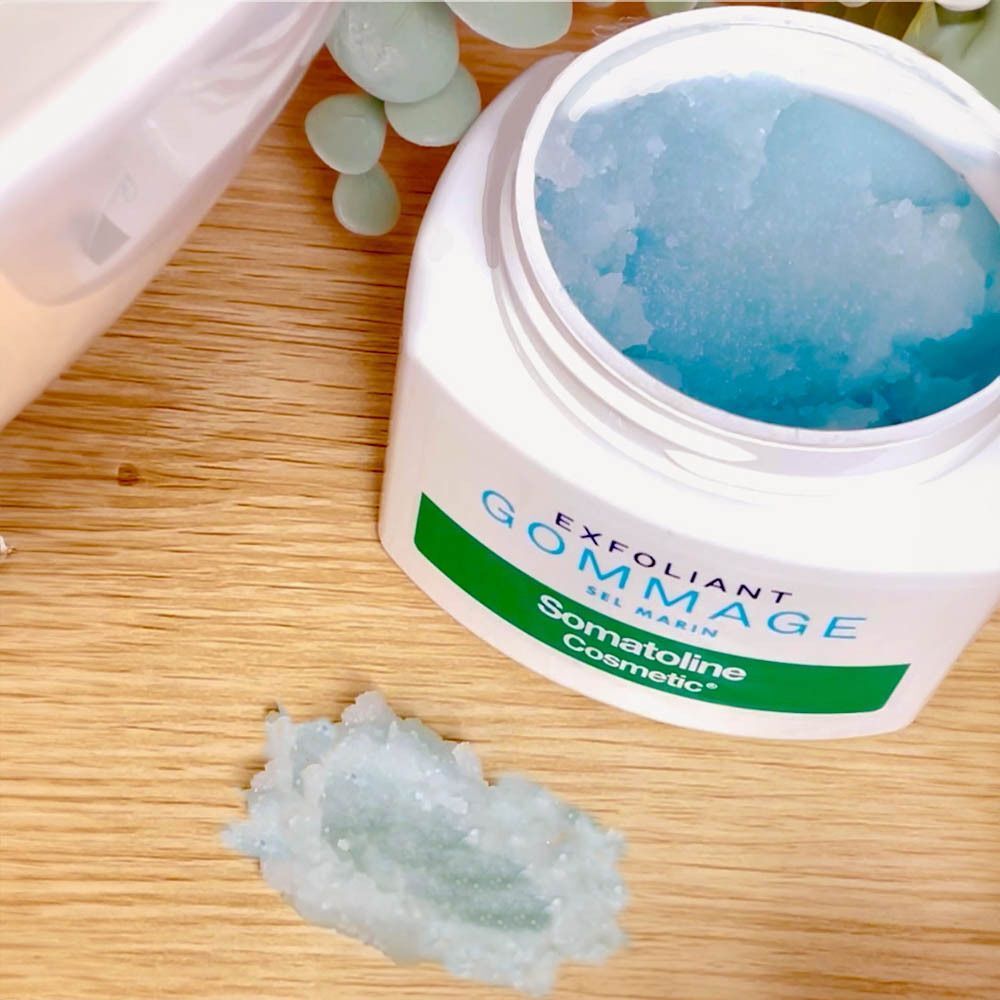 Open pot met blauwe peeling. Daarnaast klontjes peeling. Opschrift: EXFOLIANT GOMMAGE, Somatoline Cosmetic.