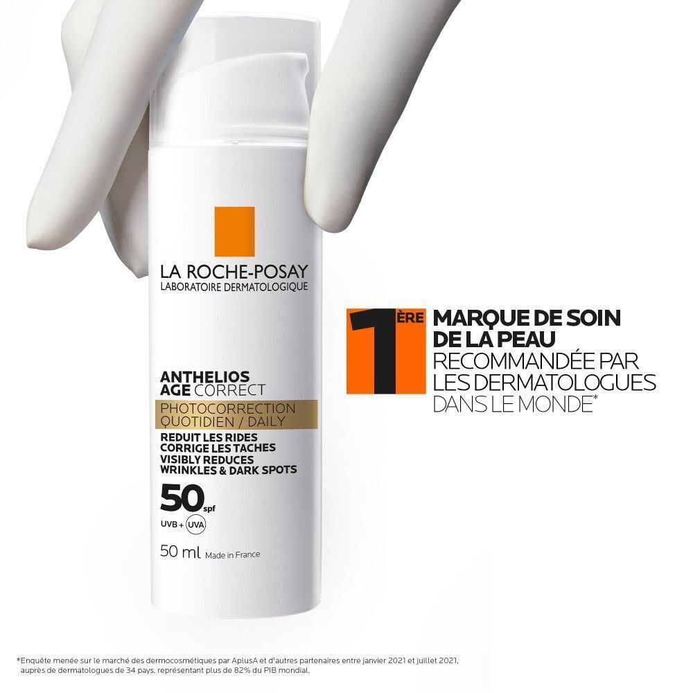 Une main gantée tient un flacon La Roche-Posay Anthelios Age Correct SPF50 avec sceau dermatologue.