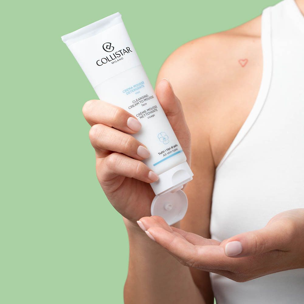 Persoon houdt een witte tube vast. Product wordt in de hand gedrukt. Tekst: Cleansing Cream To Mousse.