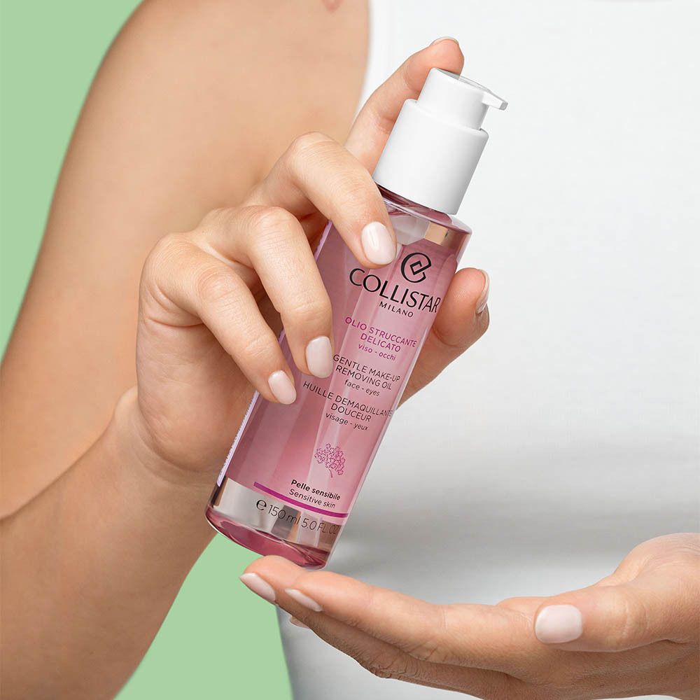 Een vrouw houdt een fles vast. Roze vloeistof in een transparante fles met witte pomp.