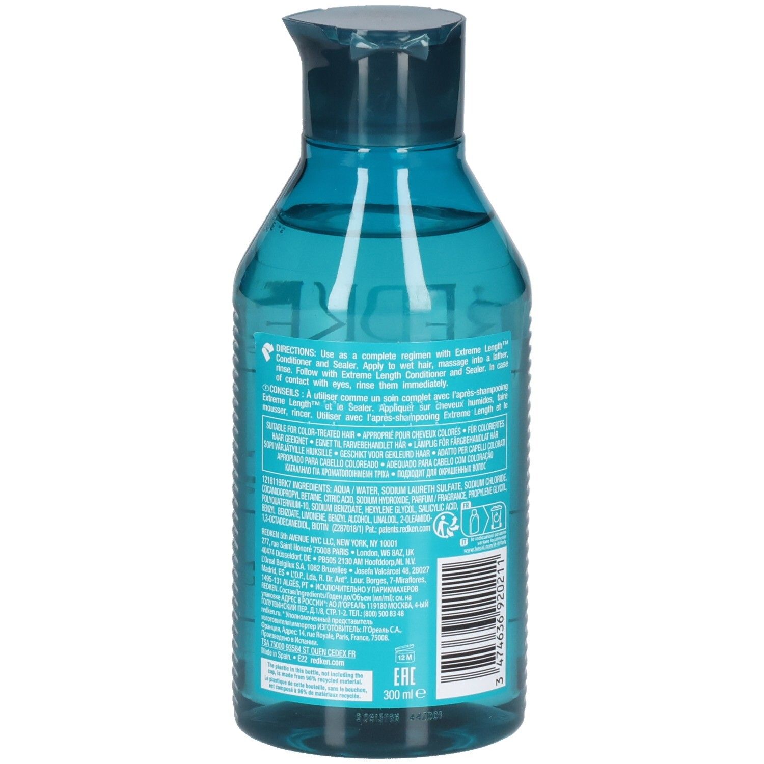 Achterkant van een blauwe, transparante shampoo fles. Barcode en tekst. Bevat ingrediënten en instructies.