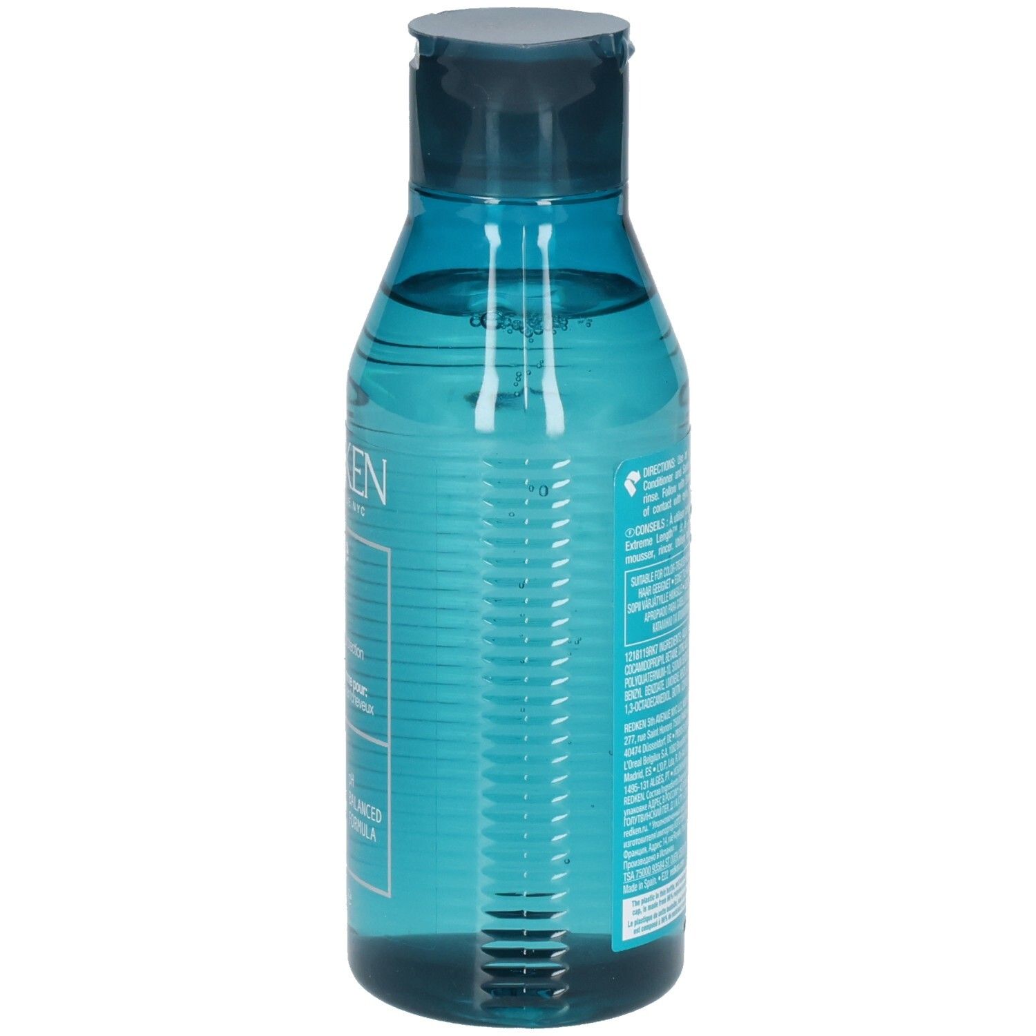 Achterkant van een blauwe, transparante shampoo fles. Barcode en tekst. Bevat ingrediënten en instructies.
