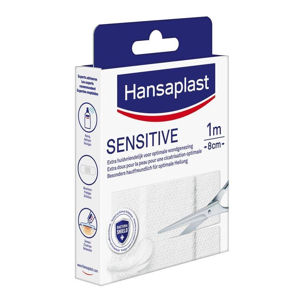 Verpakking Hansaplast Sensitive Pansement. Witte pleisters, schaar, blauwe verpakking met logo en tekst. 1 m x 8 cm. Illustraties.