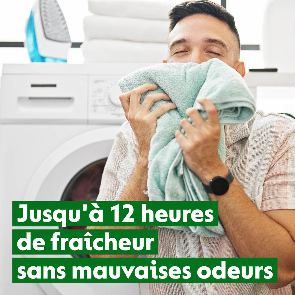 Homme sentant une serviette devant une machine à laver. Texte : 'Jusqu'à 12 heures de fraîcheur sans mauvaises odeurs'.