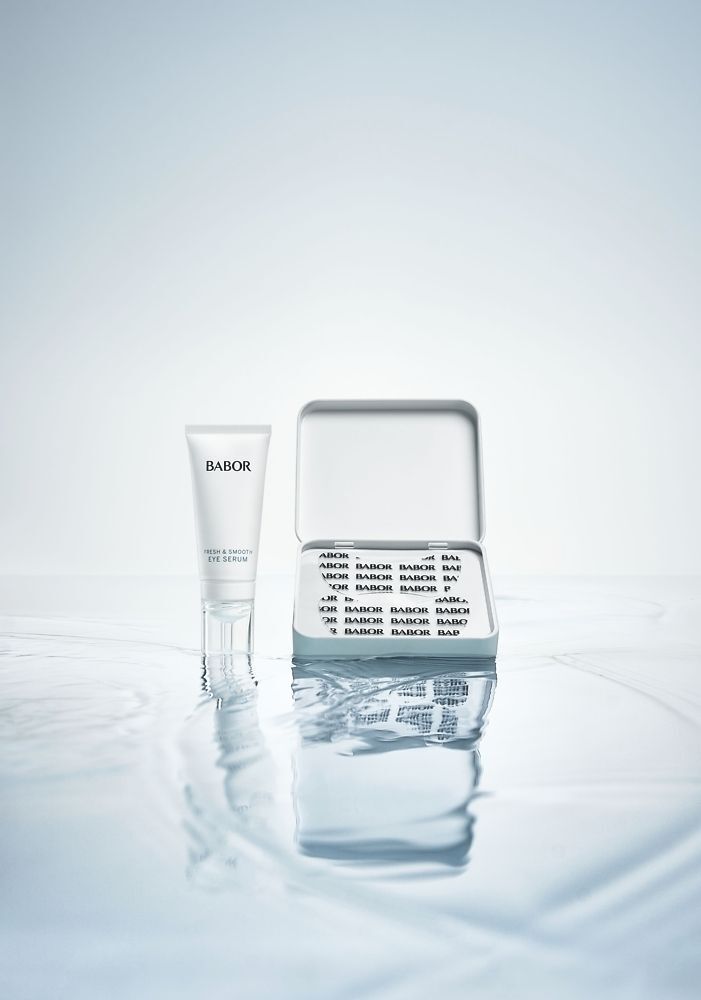 Een tube serum en een open doosje met oogpatches. Op water. Op de tube staat BABOR.