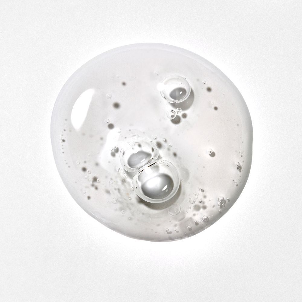 Close-up van een heldere vloeistof met bellen. De vloeistof is verdeeld over een wit oppervlak.