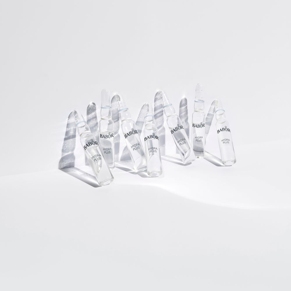 Meerdere Babor Hydra Plus ampullen op een wit oppervlak. De ampullen werpen schaduwen.