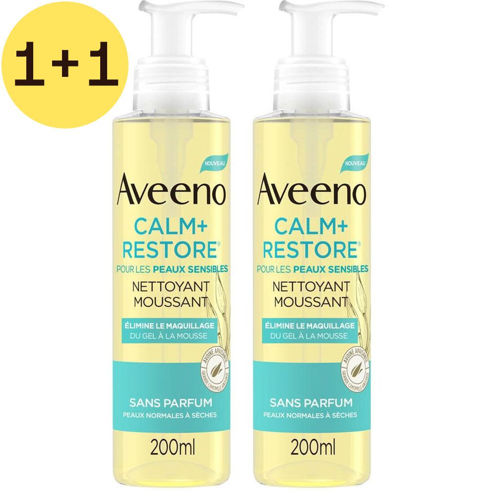 Deux flacons de nettoyant moussant Aveeno Calm+Restore. Liquide jaunâtre, pompe blanche, étiquettes turquoise. 1+1 gratuit.