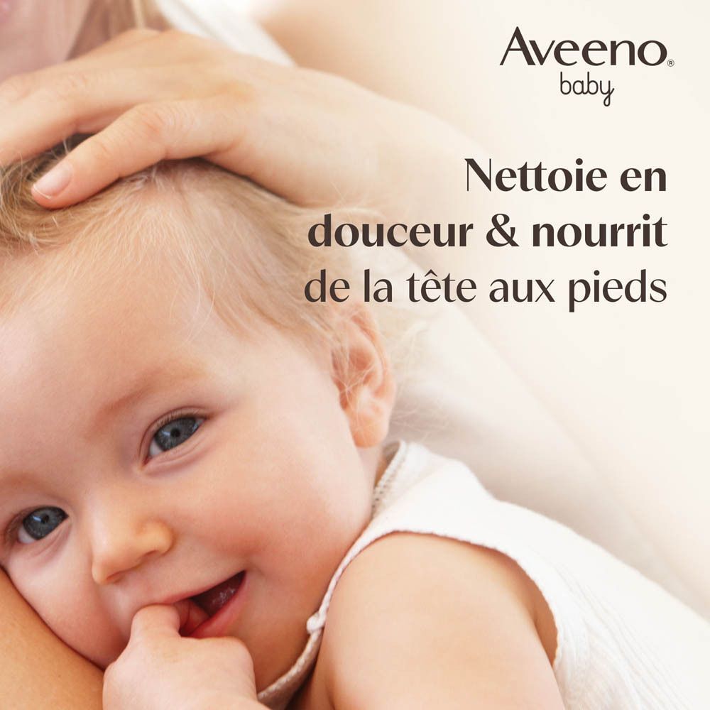 Visage de bébé tenu par une main. Texte: Nettoie en douceur & nourrit de la tête aux pieds. Logo Aveeno Baby.