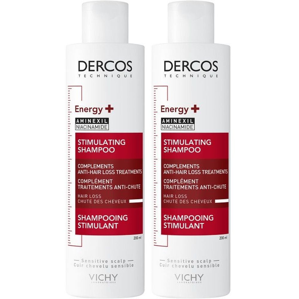 Twee witte shampoo flessen met rood etiket. Opschrift: Dercos, Energy+, Stimulating Shampoo, Vichy.