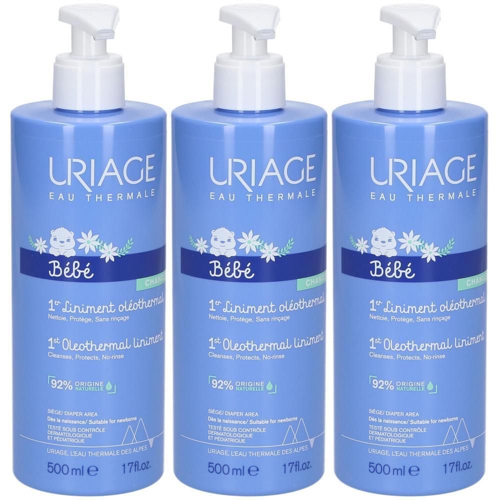 Trois flacons bleus Uriage Bébé 1er Liniment oléothermal. Avec pompe, bouchon blanc et informations produit.