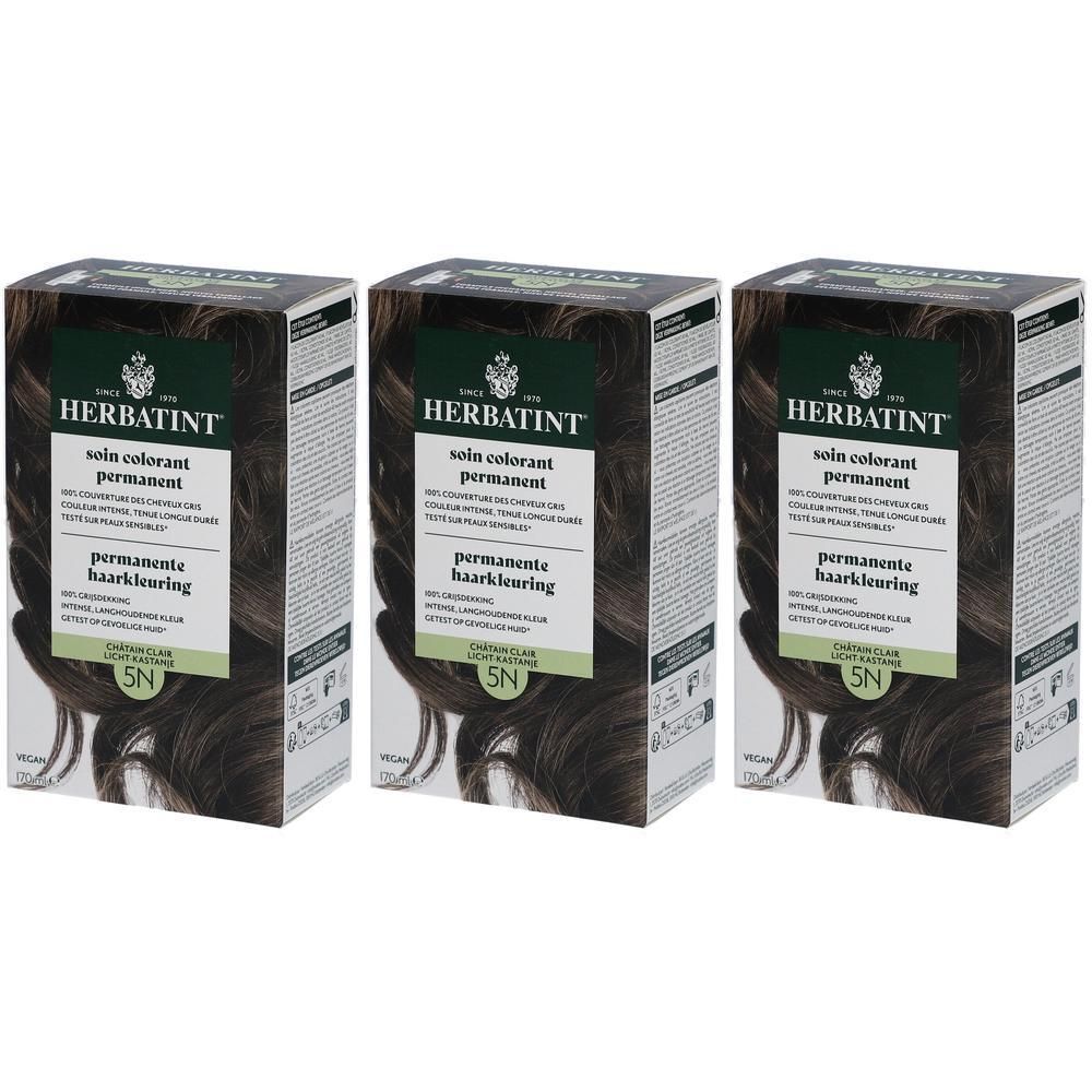 Trois boîtes de Herbatint soin colorant permanent. Emballage brun foncé avec informations et mèche de cheveux.