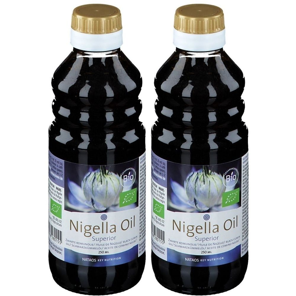 Twee flessen Nigella Oil Superior. Zwarte olie in geribbelde flessen. Gouden dop, witte hals. BIO-keurmerk.
