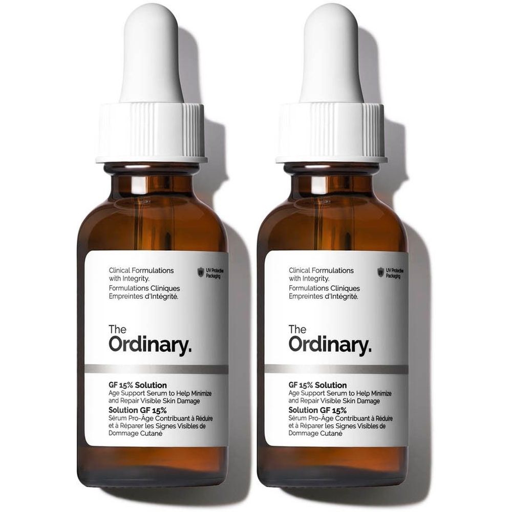 Twee bruine glazen flessen met witte etiketten en pipetten. De etiketten tonen "The Ordinary" en "GF 15% Solution".