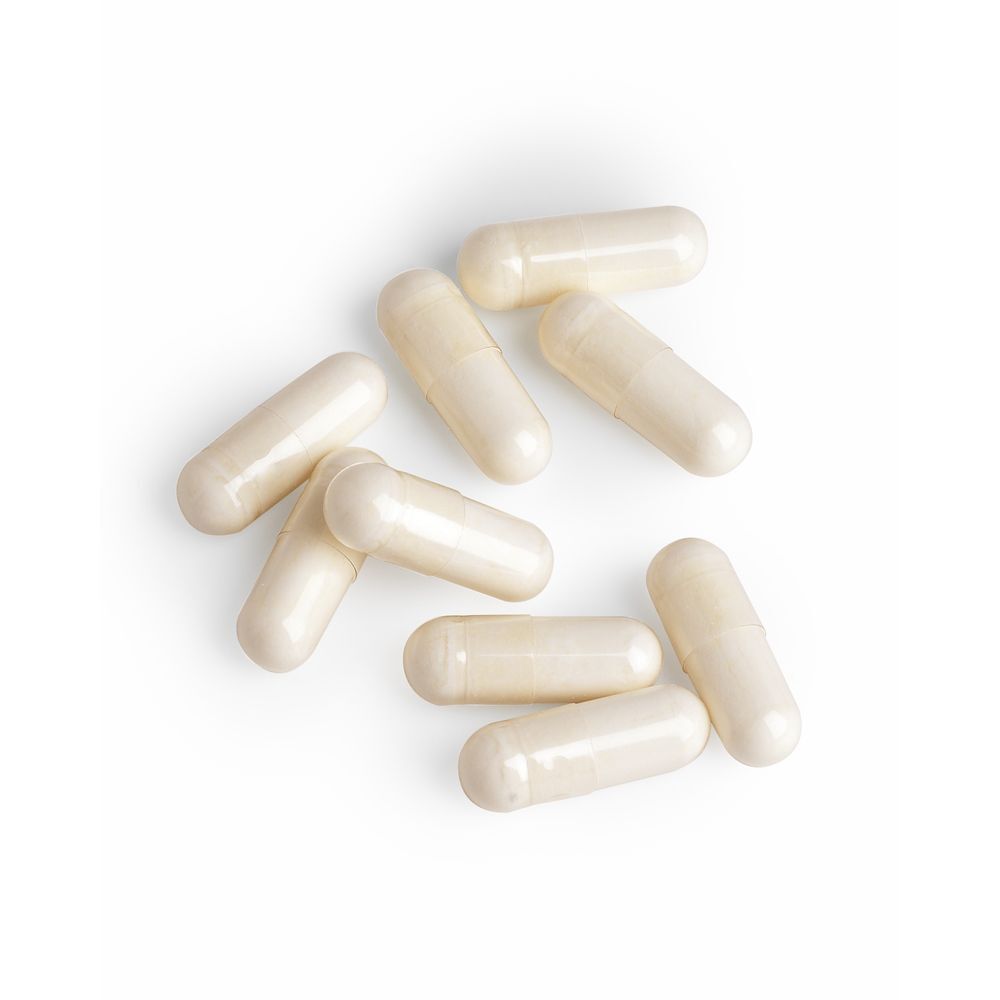 Neuf gélules crème sur fond blanc. Aucun emballage visible.