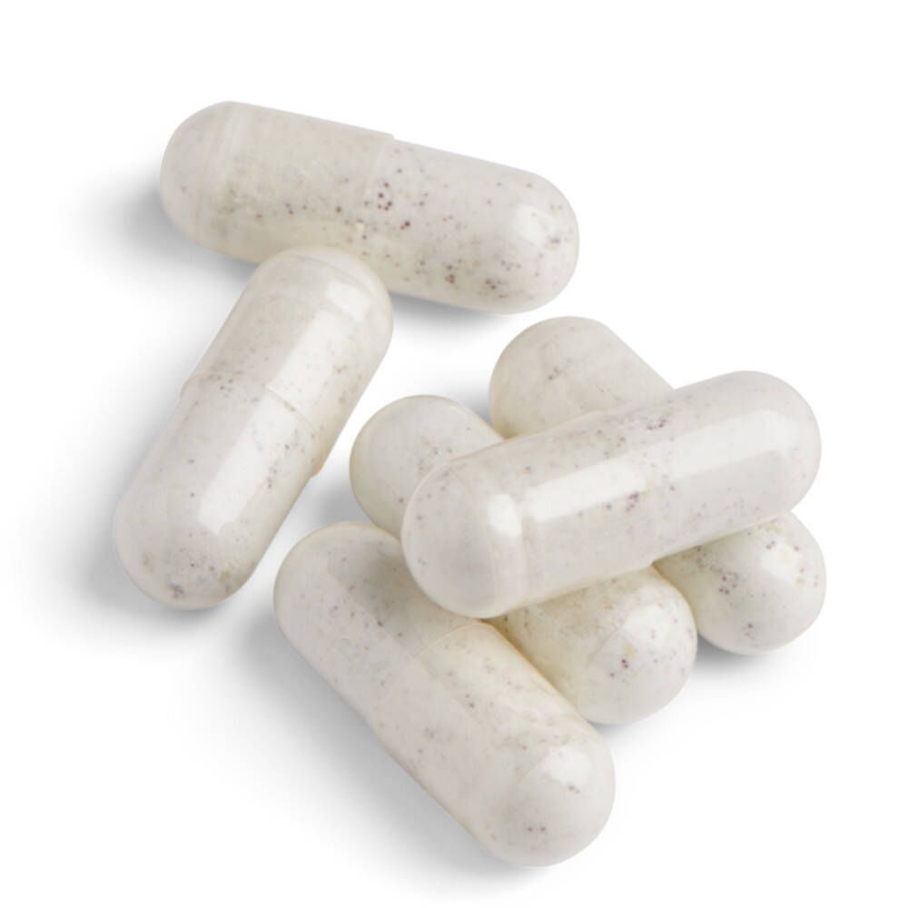 Sept gélules blanches avec de petites taches. Sur fond blanc.