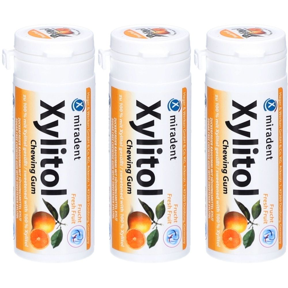 Drie witte flacons met oranje etiket. Opschrift: Xylitol Chewing Gum, miradent. Illustratie van sinaasappels. Deksel met klapdeksel.